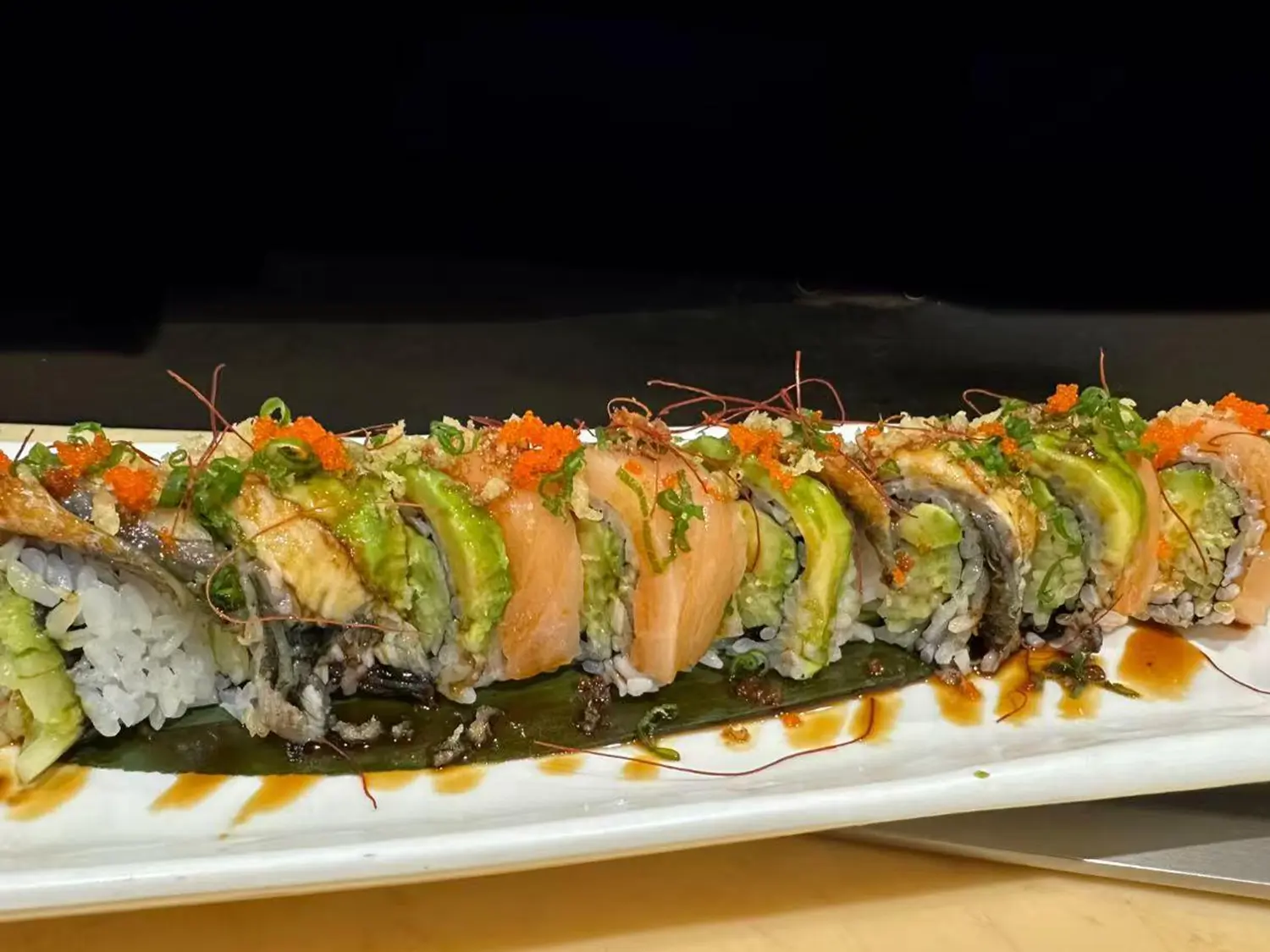 Godzilla roll topped with crispy tempura bits, spicy mayo, and avocado, offering a crunchy and zesty flavor at Hibachi Express & Sushi, a Japanese restaurant in Oklahoma City